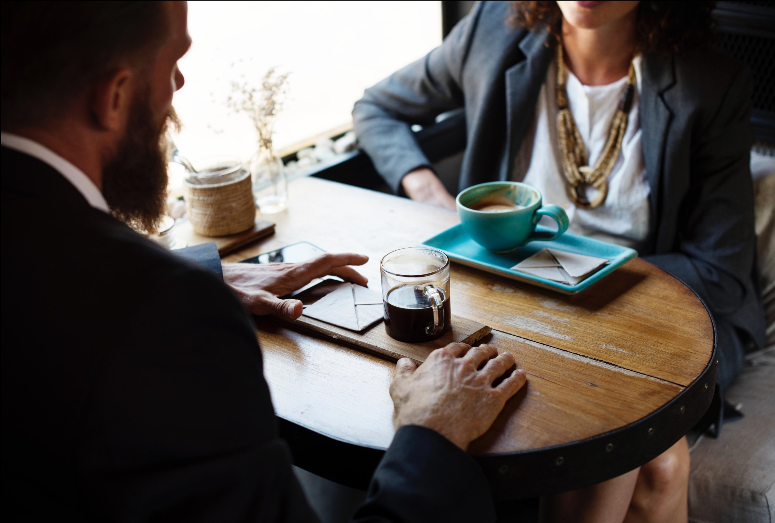 A founder and client in a warm, considered conversation over coffee